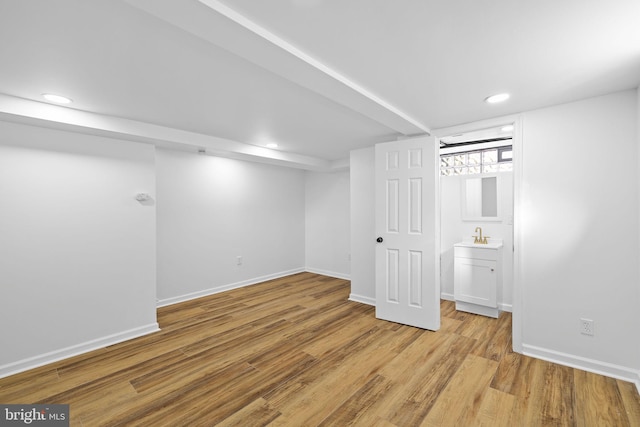 basement featuring sink and light wood-type flooring