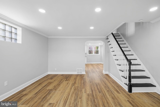 basement featuring wood-type flooring and crown molding