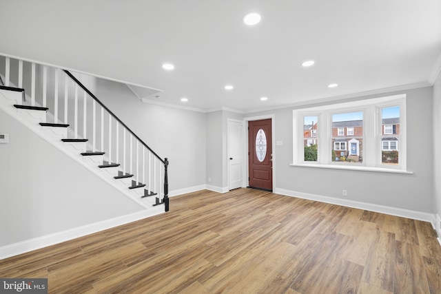 foyer entrance with light hardwood / wood-style floors and ornamental molding