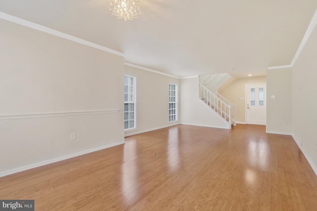 unfurnished living room featuring crown molding, a notable chandelier, and light wood-type flooring