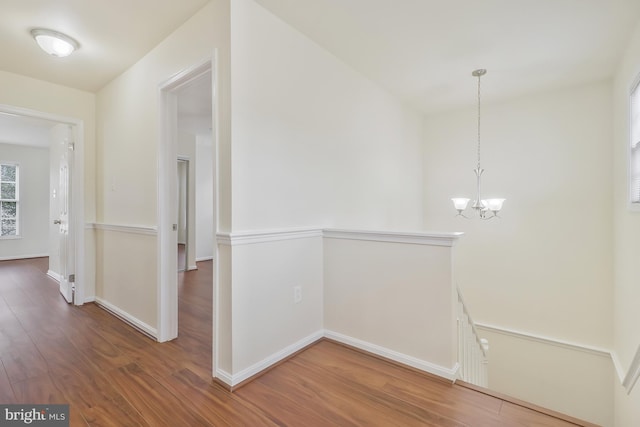 corridor with hardwood / wood-style floors and a chandelier