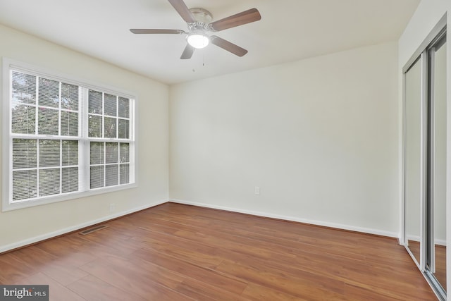 unfurnished bedroom with hardwood / wood-style flooring, ceiling fan, and a closet