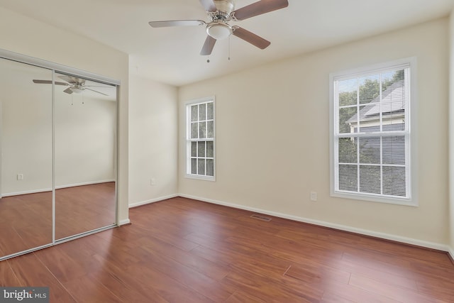 unfurnished bedroom featuring hardwood / wood-style floors, ceiling fan, and a closet