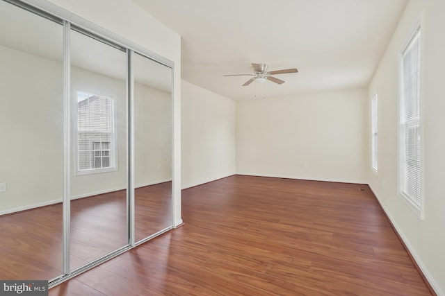 unfurnished bedroom with a closet, dark hardwood / wood-style floors, and ceiling fan