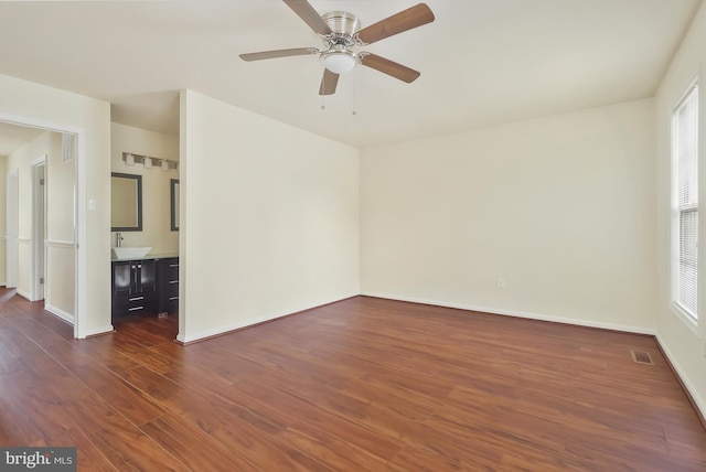 unfurnished room featuring dark hardwood / wood-style flooring, ceiling fan, and sink