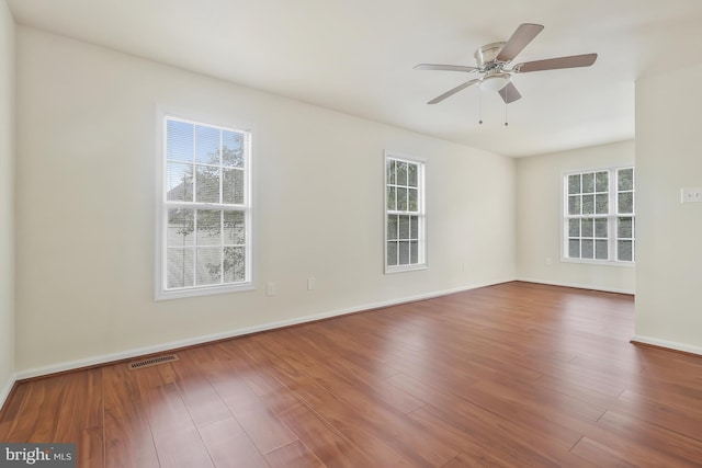 empty room with hardwood / wood-style floors, a wealth of natural light, and ceiling fan