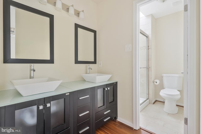 bathroom featuring hardwood / wood-style flooring, vanity, an enclosed shower, and toilet