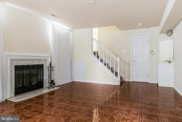 unfurnished living room featuring a premium fireplace and sink