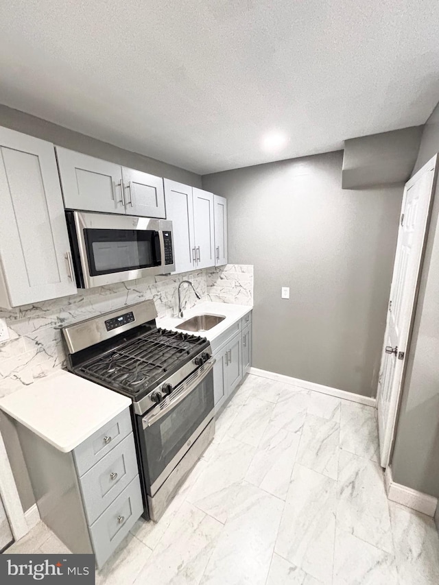 kitchen with a textured ceiling, stainless steel appliances, tasteful backsplash, and sink