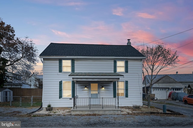 front facade with covered porch and a shed