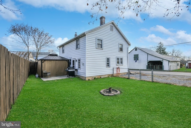 rear view of house featuring a gazebo, a yard, and an outdoor fire pit