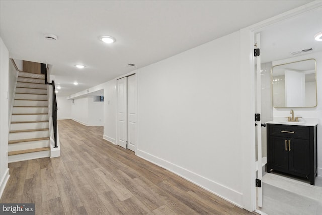 basement with sink and light hardwood / wood-style flooring