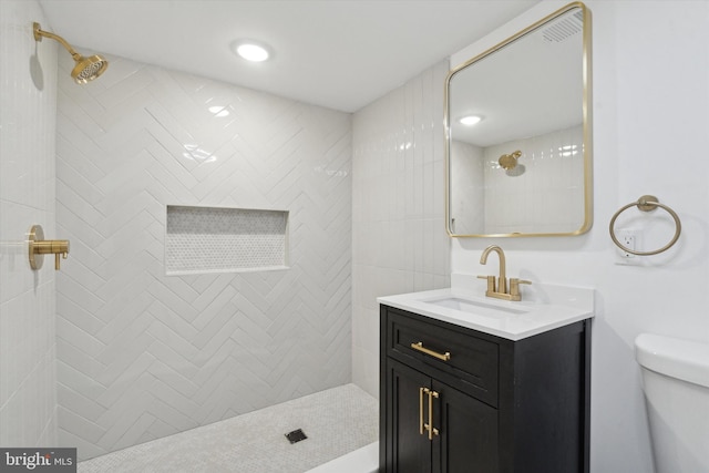 bathroom with vanity, toilet, and tiled shower