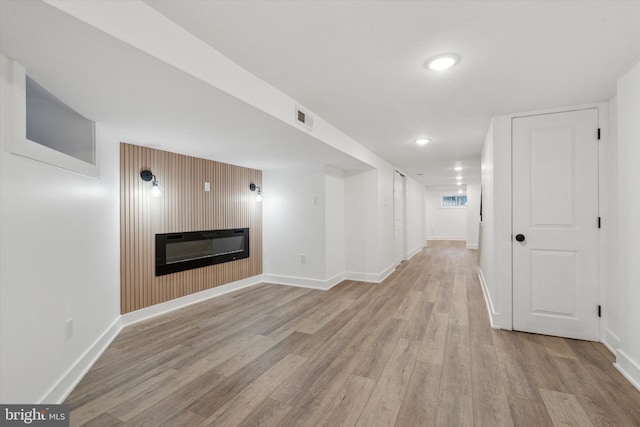 corridor with wooden walls and light hardwood / wood-style flooring