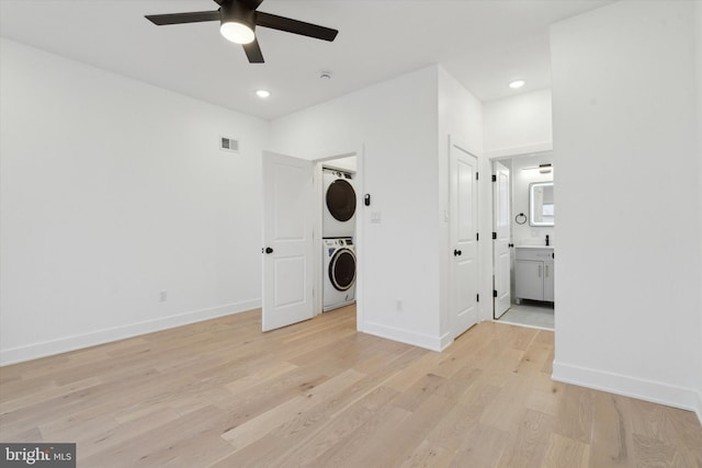 clothes washing area with ceiling fan, stacked washer / drying machine, and light wood-type flooring