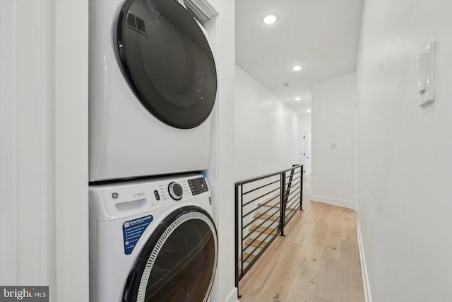 clothes washing area with light wood-type flooring and stacked washer / drying machine