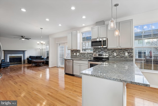 kitchen featuring pendant lighting, light wood-type flooring, stainless steel appliances, and tasteful backsplash