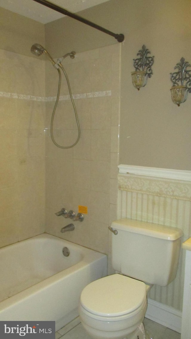 bathroom with tile patterned flooring, tiled shower / bath combo, and toilet