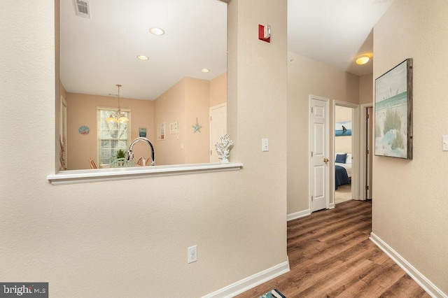 hallway with hardwood / wood-style flooring and an inviting chandelier