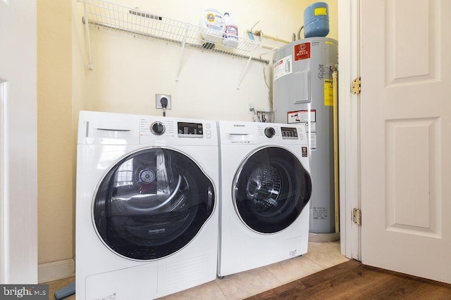 laundry room with washing machine and dryer, water heater, and hardwood / wood-style floors