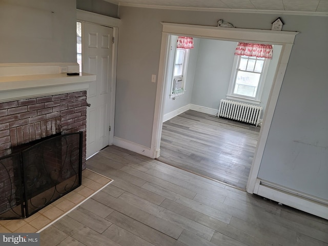 unfurnished living room with light hardwood / wood-style floors, radiator heating unit, ornamental molding, and baseboard heating