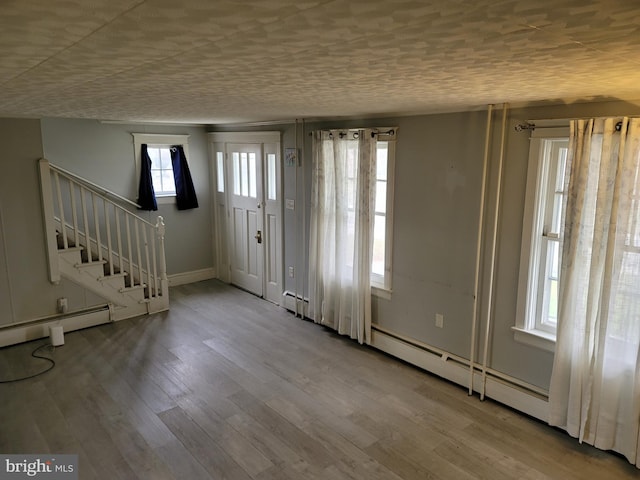 foyer featuring a baseboard heating unit, light hardwood / wood-style floors, and a healthy amount of sunlight