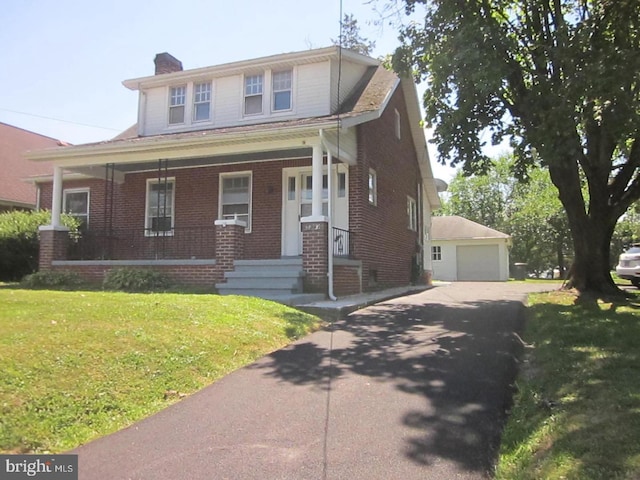 view of front of house with an outbuilding, a front lawn, covered porch, and a garage