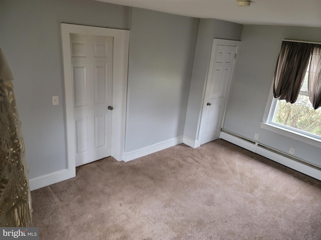 unfurnished bedroom featuring light carpet and a baseboard heating unit