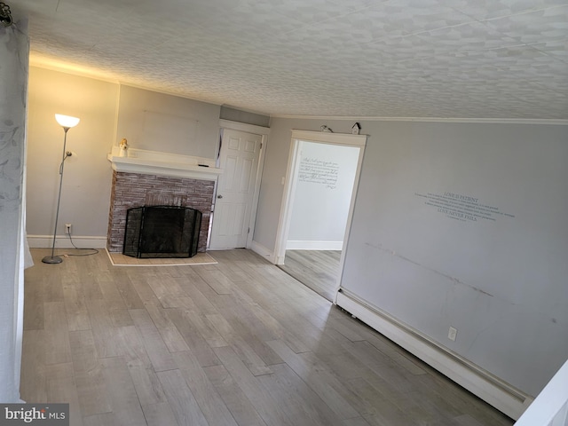 unfurnished living room featuring a fireplace, a textured ceiling, light wood-type flooring, and baseboard heating