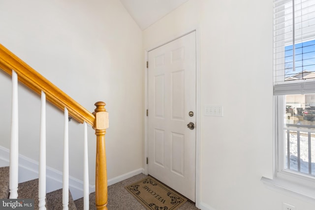 carpeted foyer entrance featuring a wealth of natural light and vaulted ceiling