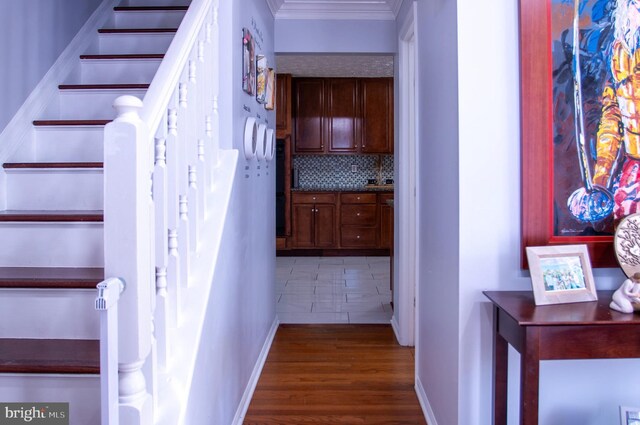 stairway with ornamental molding and hardwood / wood-style flooring