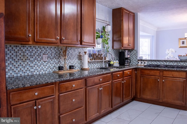 kitchen with black gas cooktop, dark stone counters, sink, ornamental molding, and tasteful backsplash