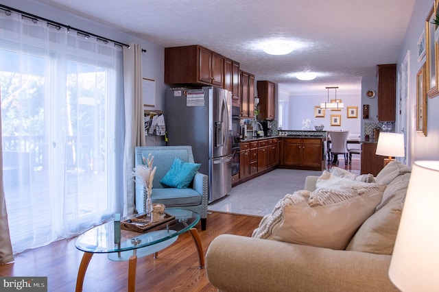 kitchen featuring hanging light fixtures, light wood-type flooring, stainless steel refrigerator with ice dispenser, and a wealth of natural light