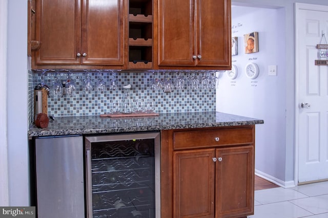 kitchen with dark stone countertops, decorative backsplash, light tile patterned floors, and beverage cooler