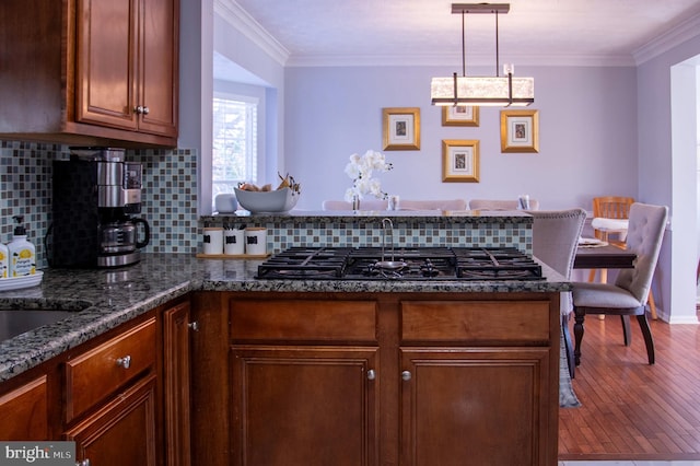 kitchen with decorative backsplash, gas stovetop, crown molding, hardwood / wood-style floors, and hanging light fixtures