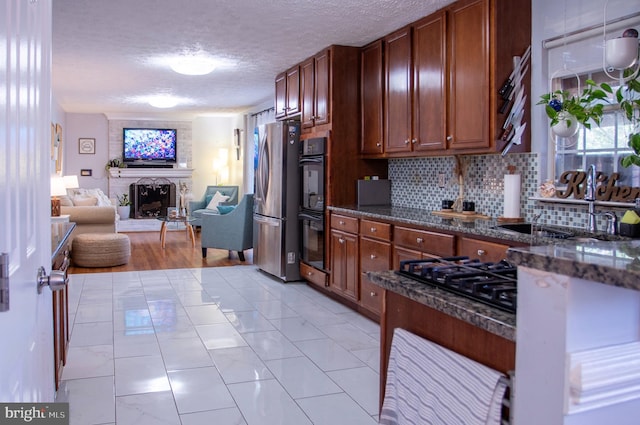 kitchen featuring sink, tasteful backsplash, dark stone counters, a textured ceiling, and black appliances