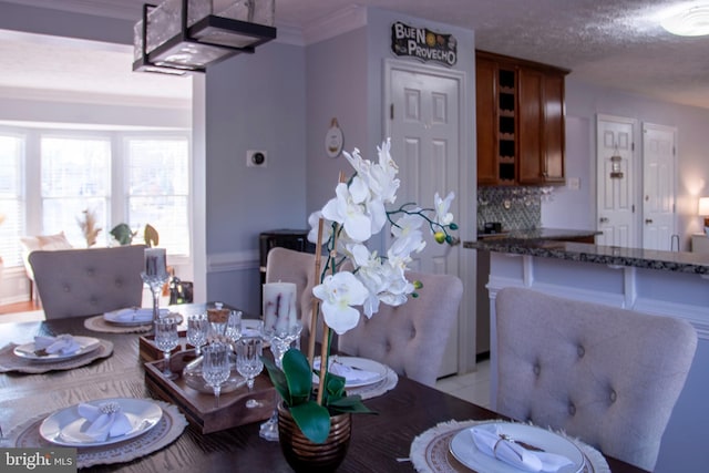 tiled dining area with a textured ceiling and crown molding