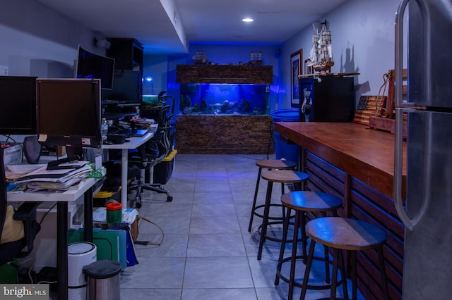 bar with stainless steel fridge and light tile patterned floors