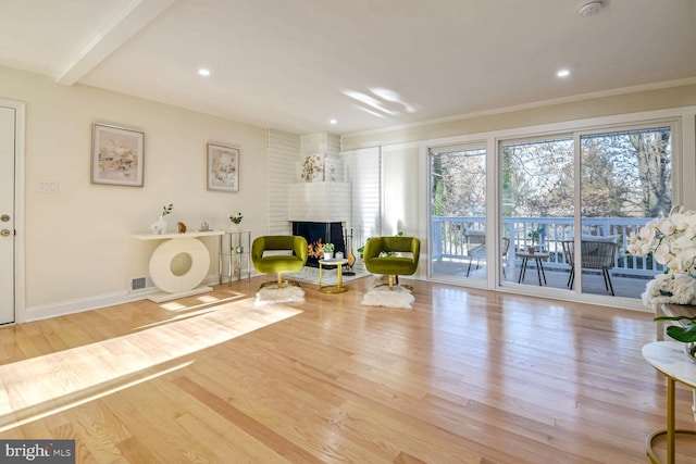 exercise room with ornamental molding, a fireplace, and light hardwood / wood-style flooring