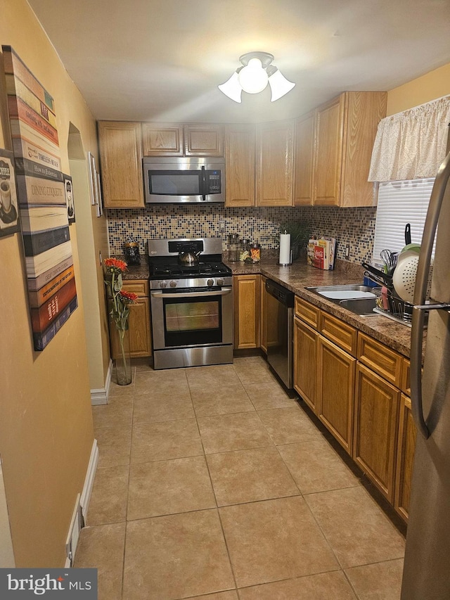 kitchen featuring decorative backsplash, light tile patterned floors, sink, and appliances with stainless steel finishes