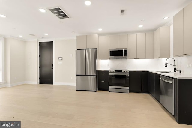 kitchen with tasteful backsplash, sink, light hardwood / wood-style flooring, and appliances with stainless steel finishes