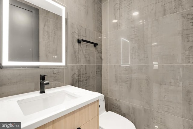 bathroom with backsplash, vanity, tile walls, and toilet