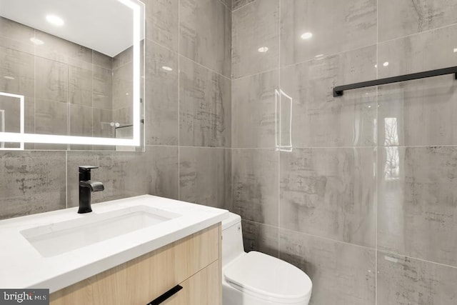 bathroom with vanity, toilet, tile walls, and backsplash