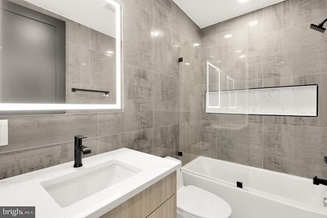 full bathroom with toilet, vanity, tile walls, and tub / shower combination