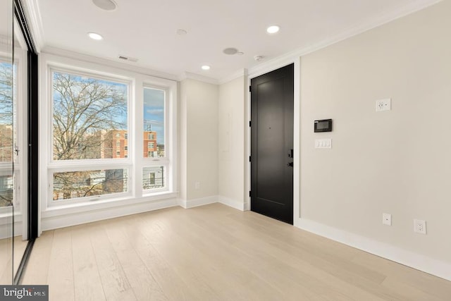 empty room featuring crown molding and light hardwood / wood-style flooring