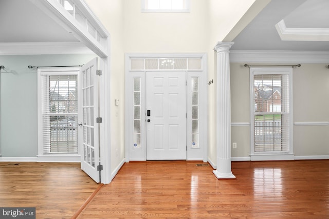 entrance foyer featuring plenty of natural light, ornamental molding, and light hardwood / wood-style flooring