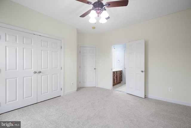 unfurnished bedroom with ceiling fan, light colored carpet, ensuite bath, and a closet