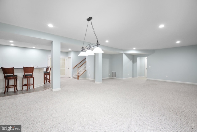 basement featuring light colored carpet and bar area