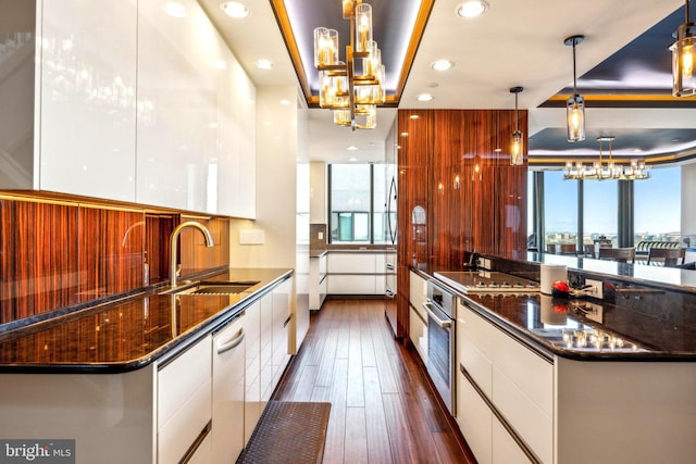 kitchen featuring modern cabinets, a sink, decorative light fixtures, and white cabinets