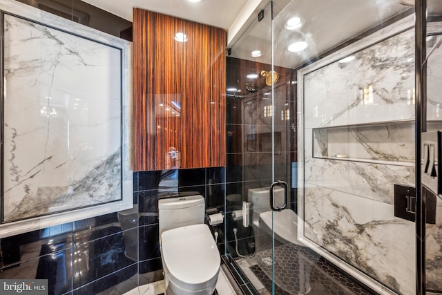 bathroom featuring toilet, a shower with door, and tile walls